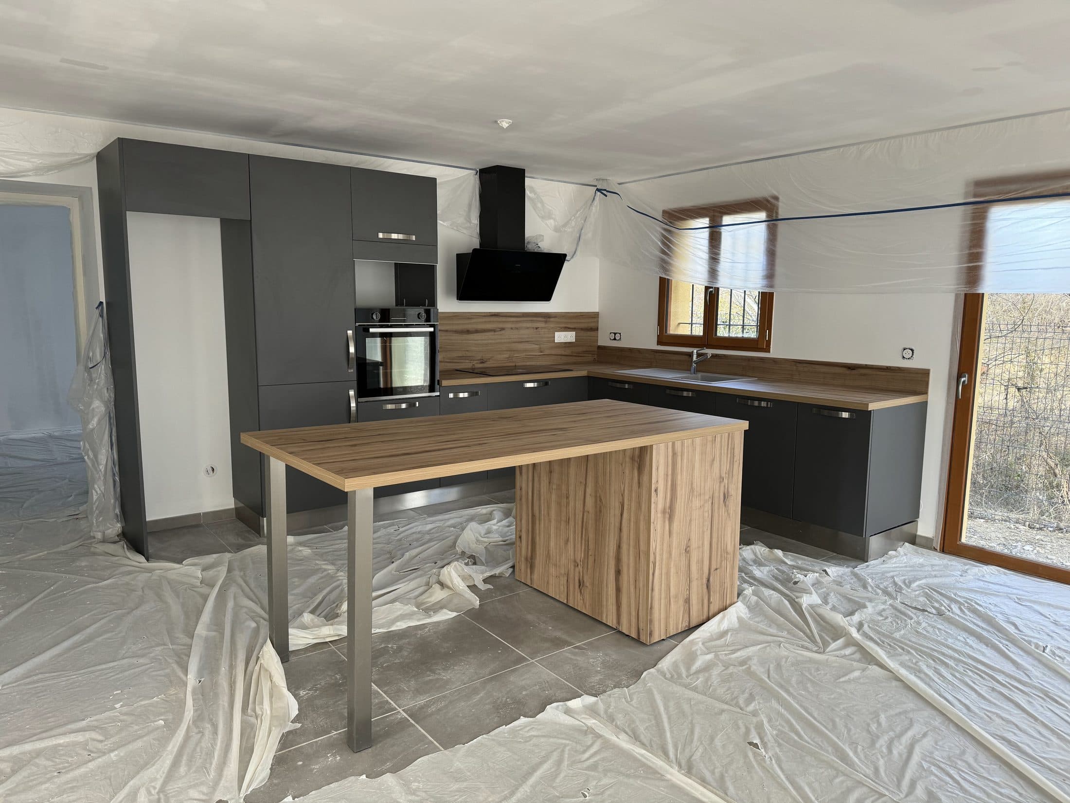 Cuisine anthracite avec îlot bois sur pied inox