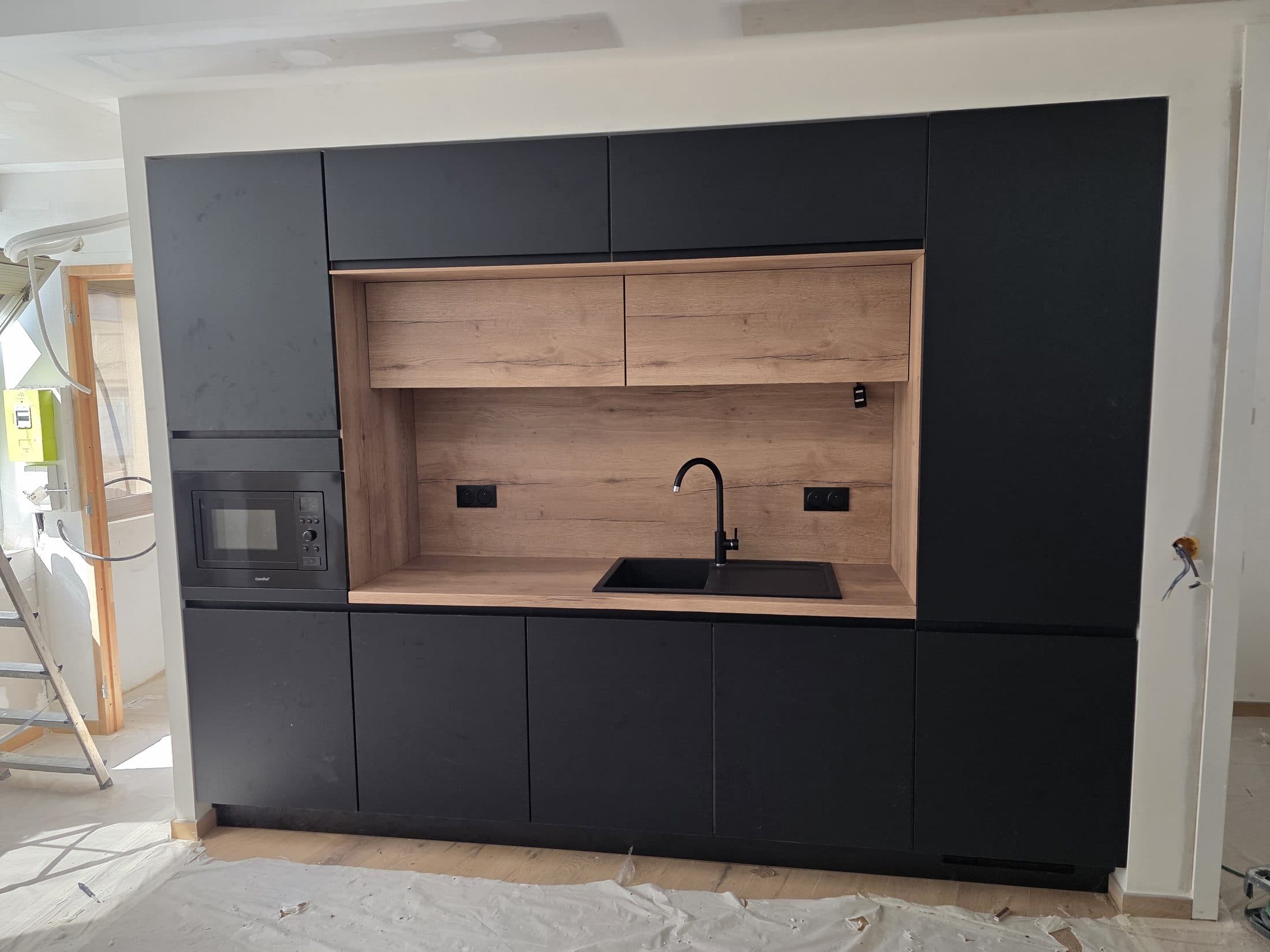 Kitchenette noire avec niche bois et micro-ondes encastré