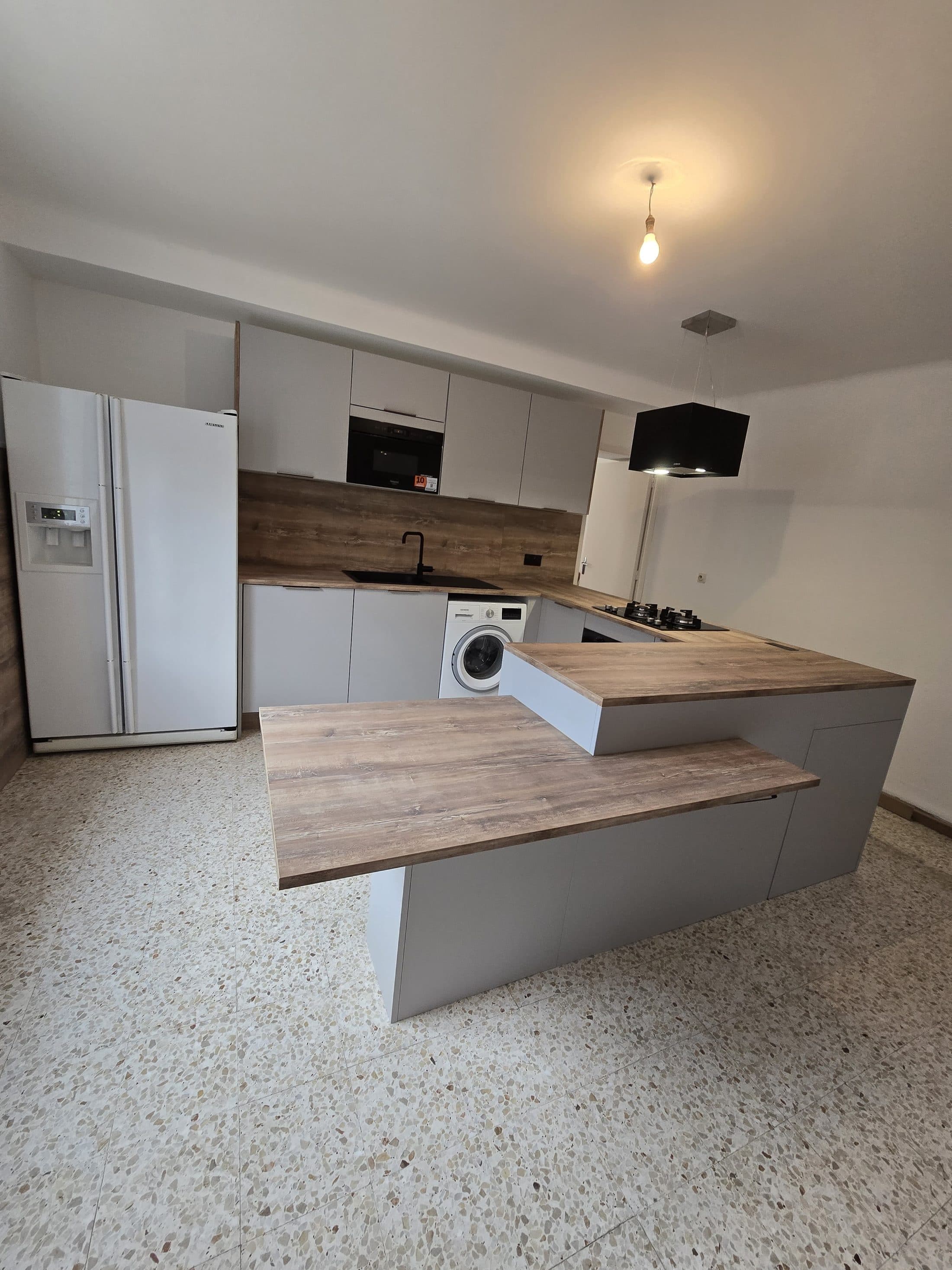 Cuisine compacte avec bar en bois sur sol terrazzo