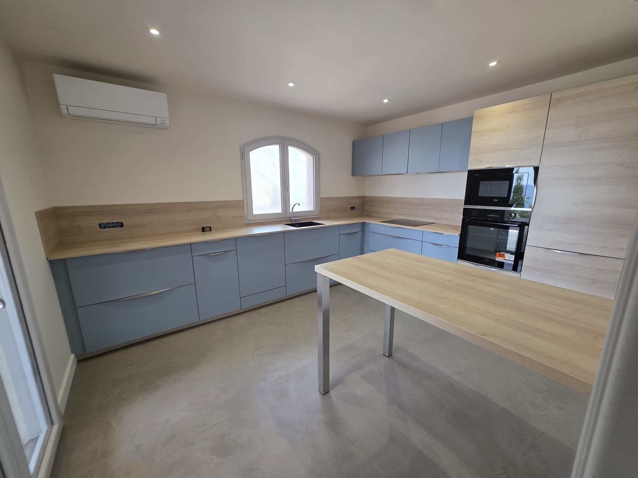 Cuisine gris-bleu avec plan de travail bois et table intégrée