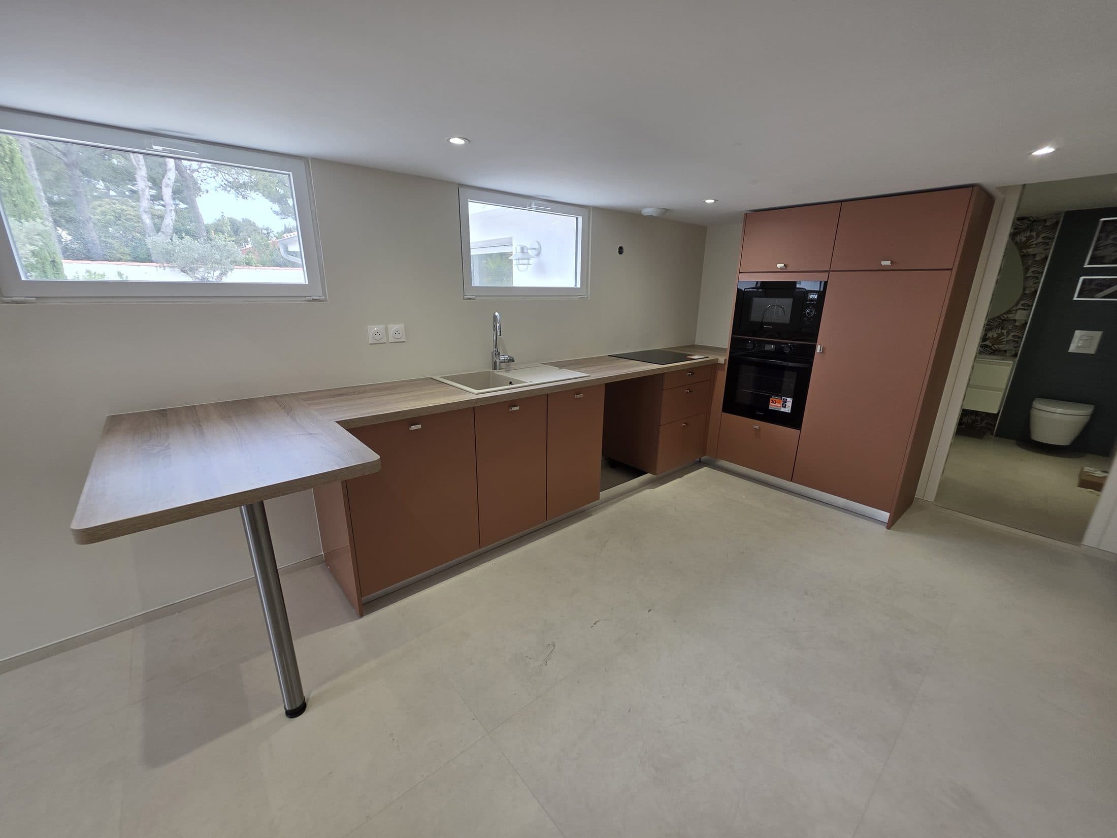 Cuisine terracotta avec bar en bois et électroménager encastré